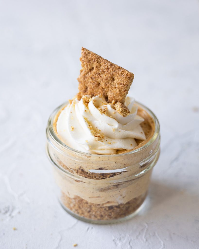A single mini pumpkin cheesecake topped with whipped cream and graham cracker shards.