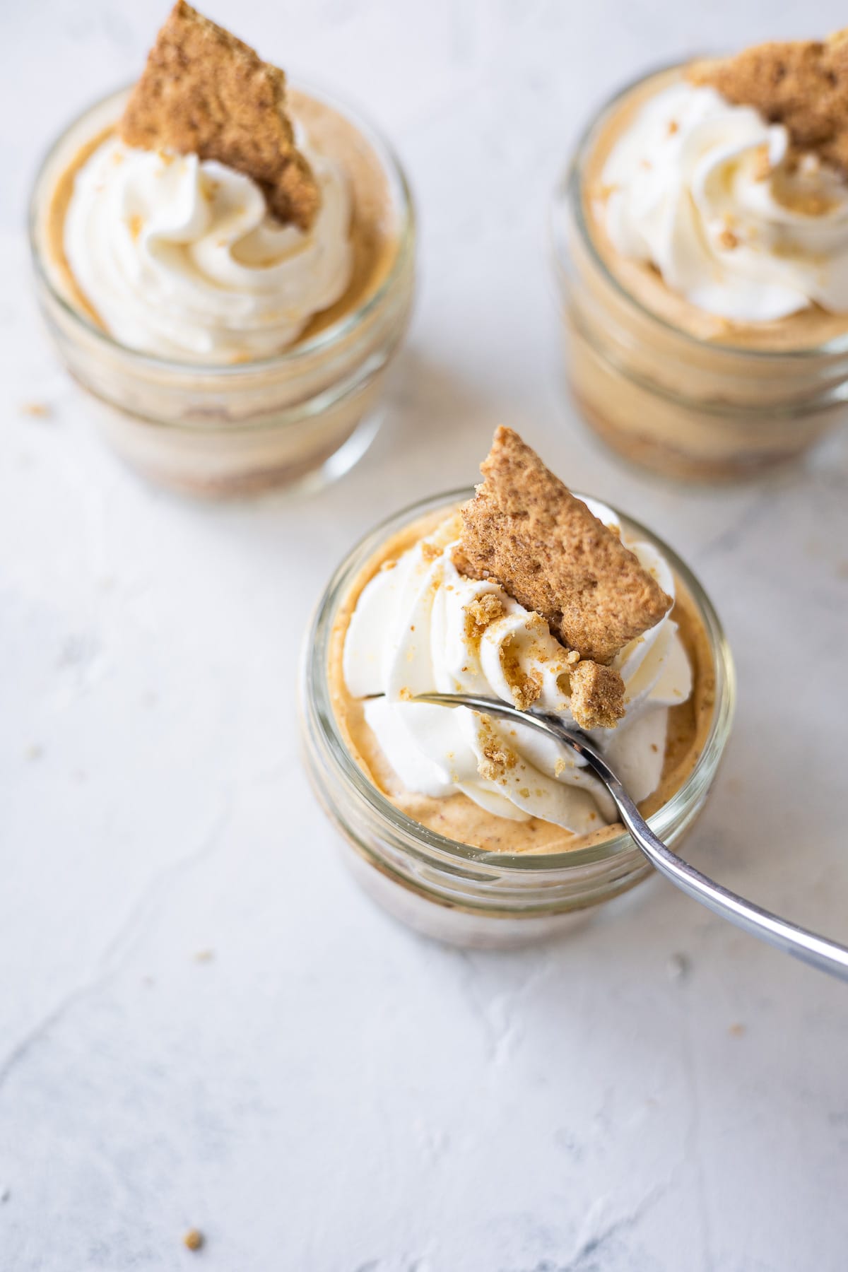 A spoon digging into a mason jar dessert topped with whipped cream.