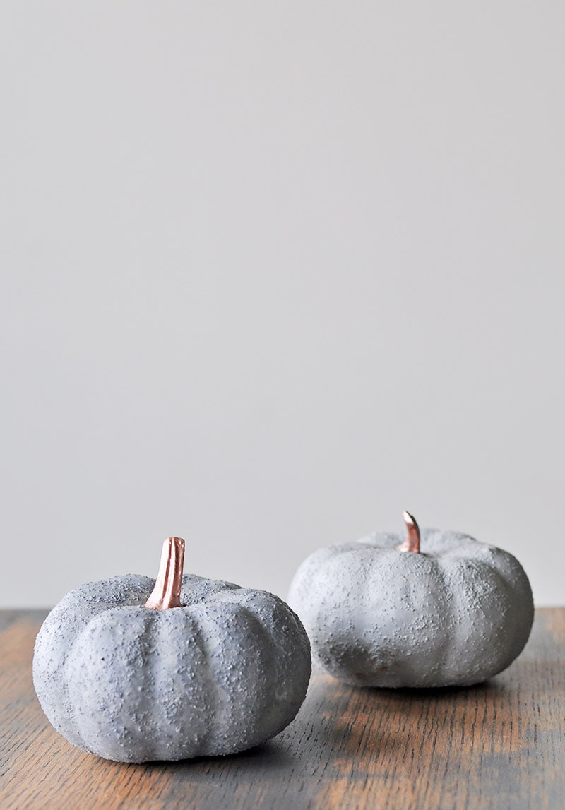 Two DIY gray concrete pumpkins with metallic stems.