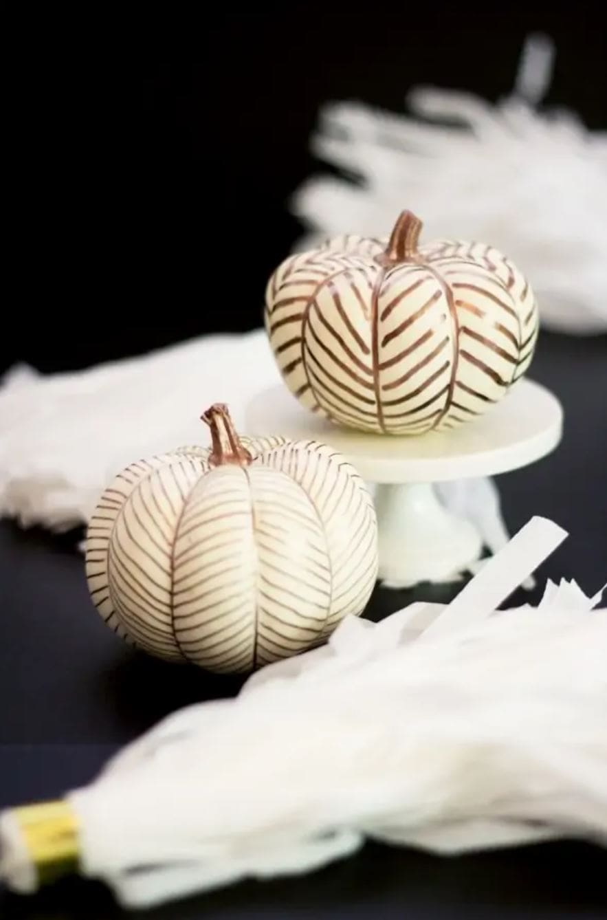White pumpkins with herringbone designs drawn on with paint markers.