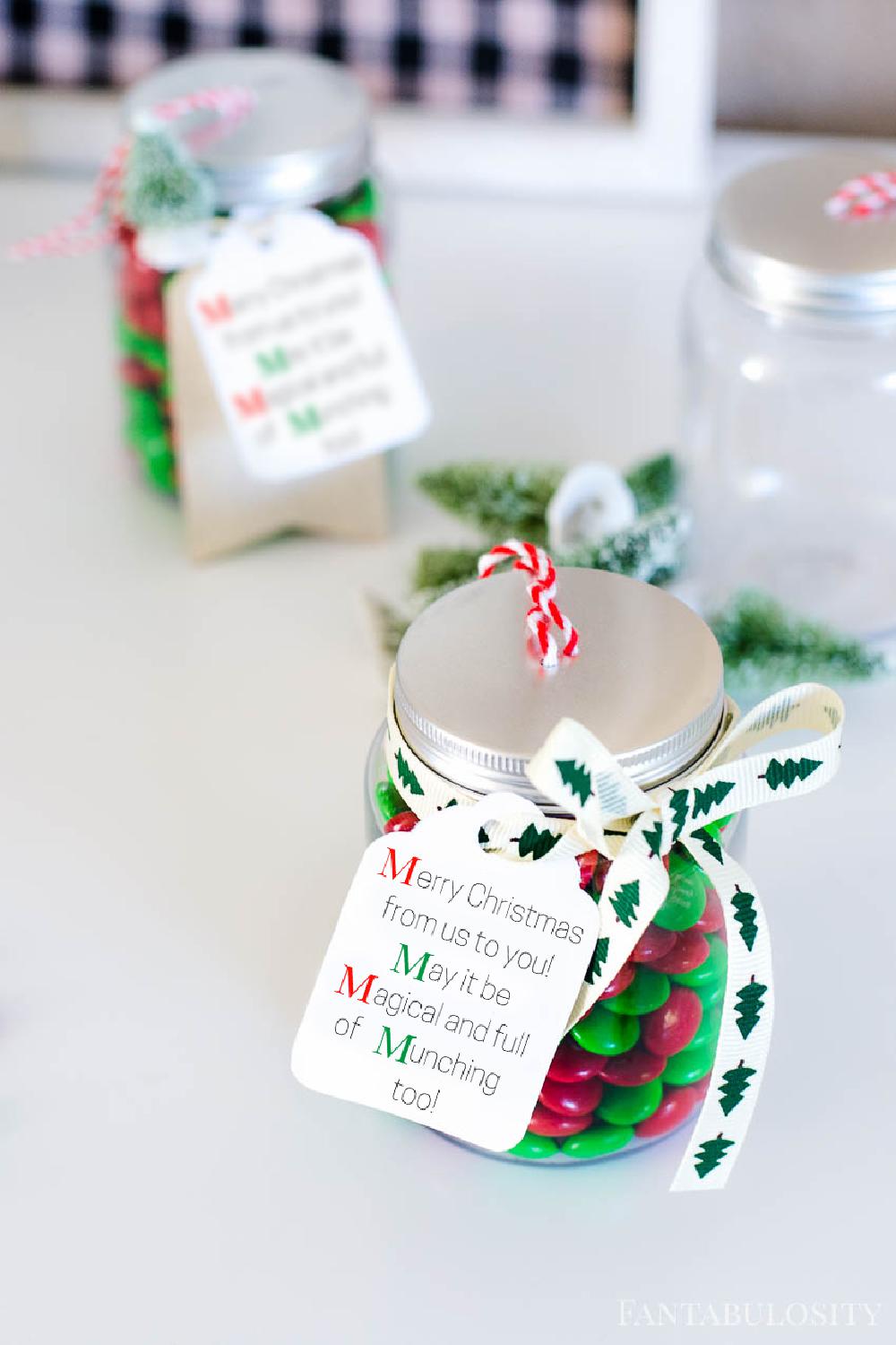 A Christmas treat jar with m&ms and a custom gift tag.