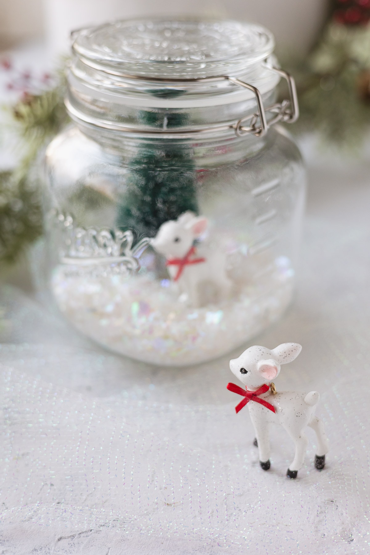 A mason jar Christmas scene and a white reindeer ornament.