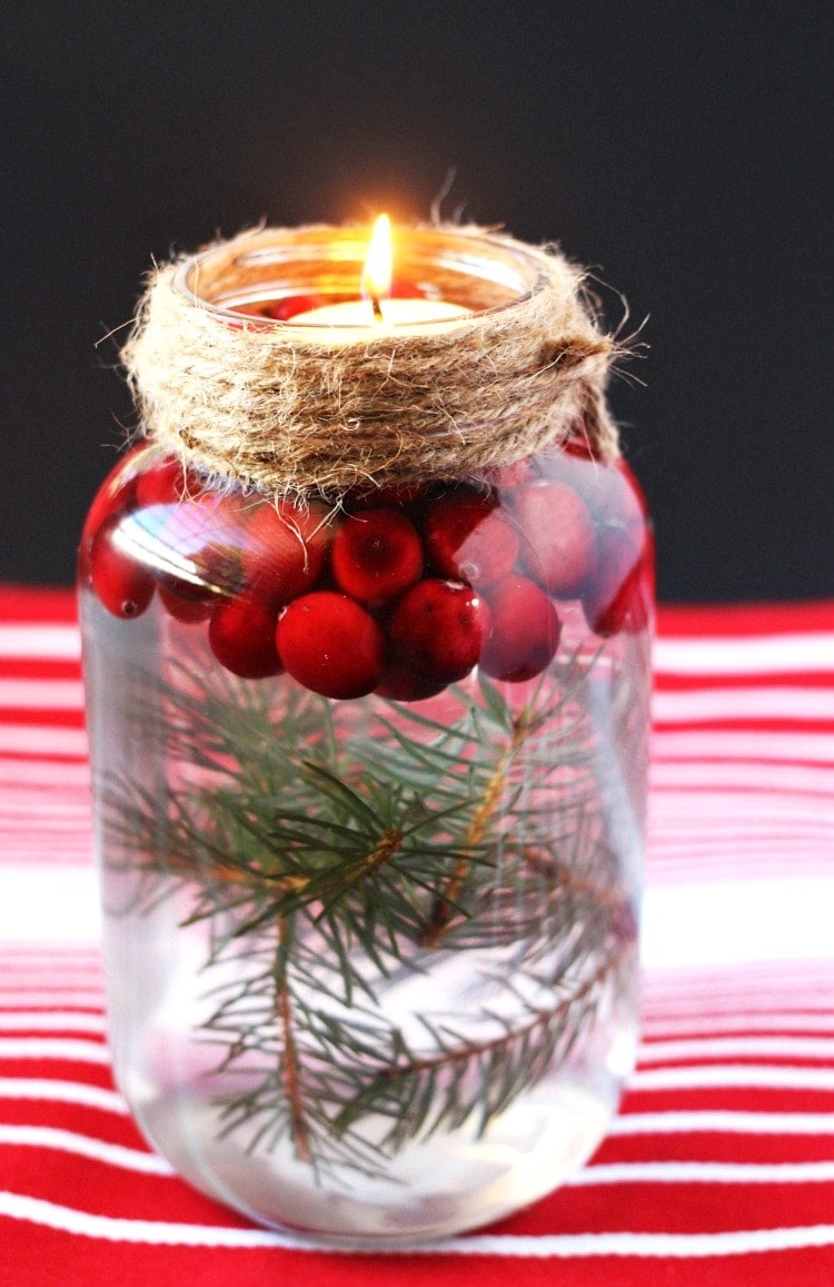 A mason jar floating candle with evergreen and cranberries.