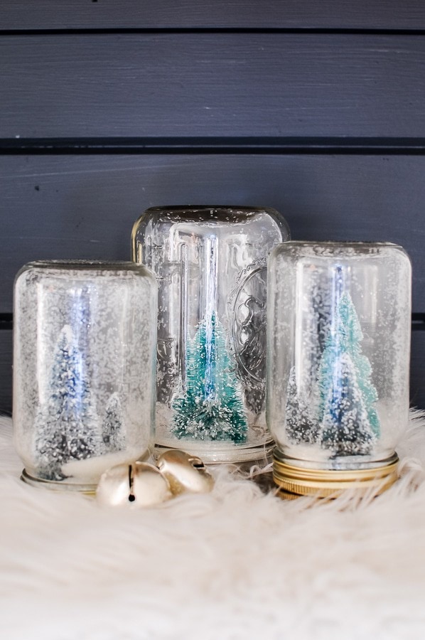 Three mason jar snow globes with bottle brush trees.
