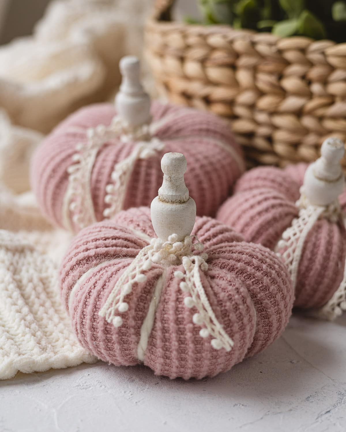 Pink sweater pumpkins decorated with lace and wooden finial stems.