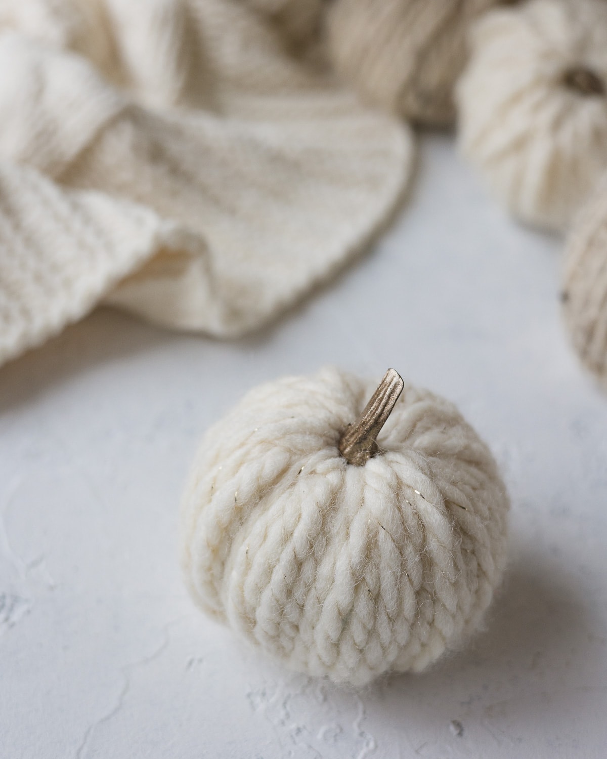 A white yarn pumpkin with a faux metallic stem.