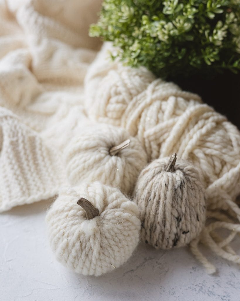 Three yarn wrapped pumpkins and a skein of thick yarn.