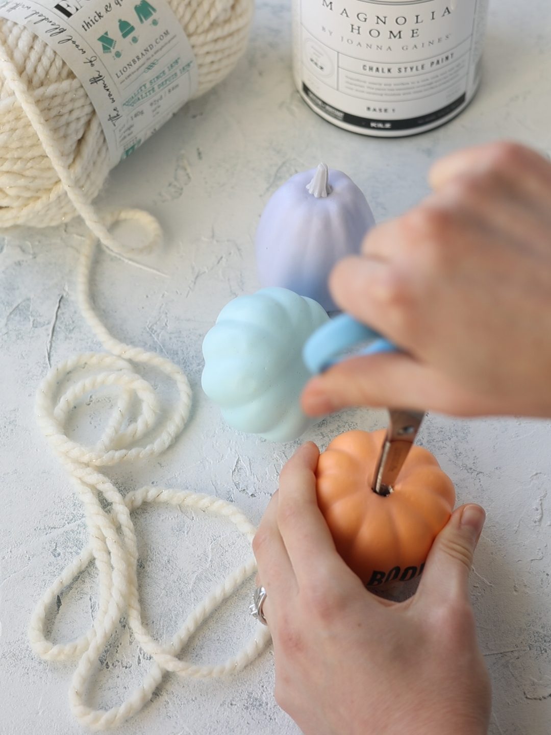 Removing the center of a faux pumpkin with scissors.