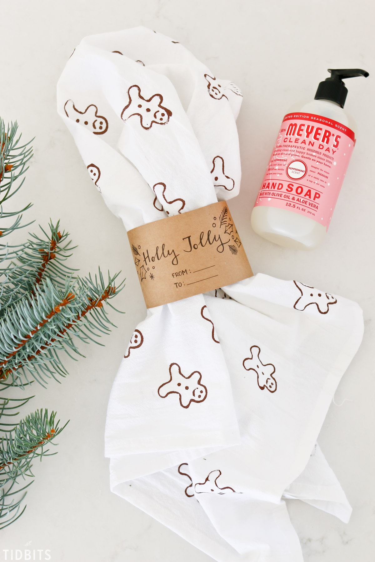 A stamped tea towel, hand soup, and evergreen branch.