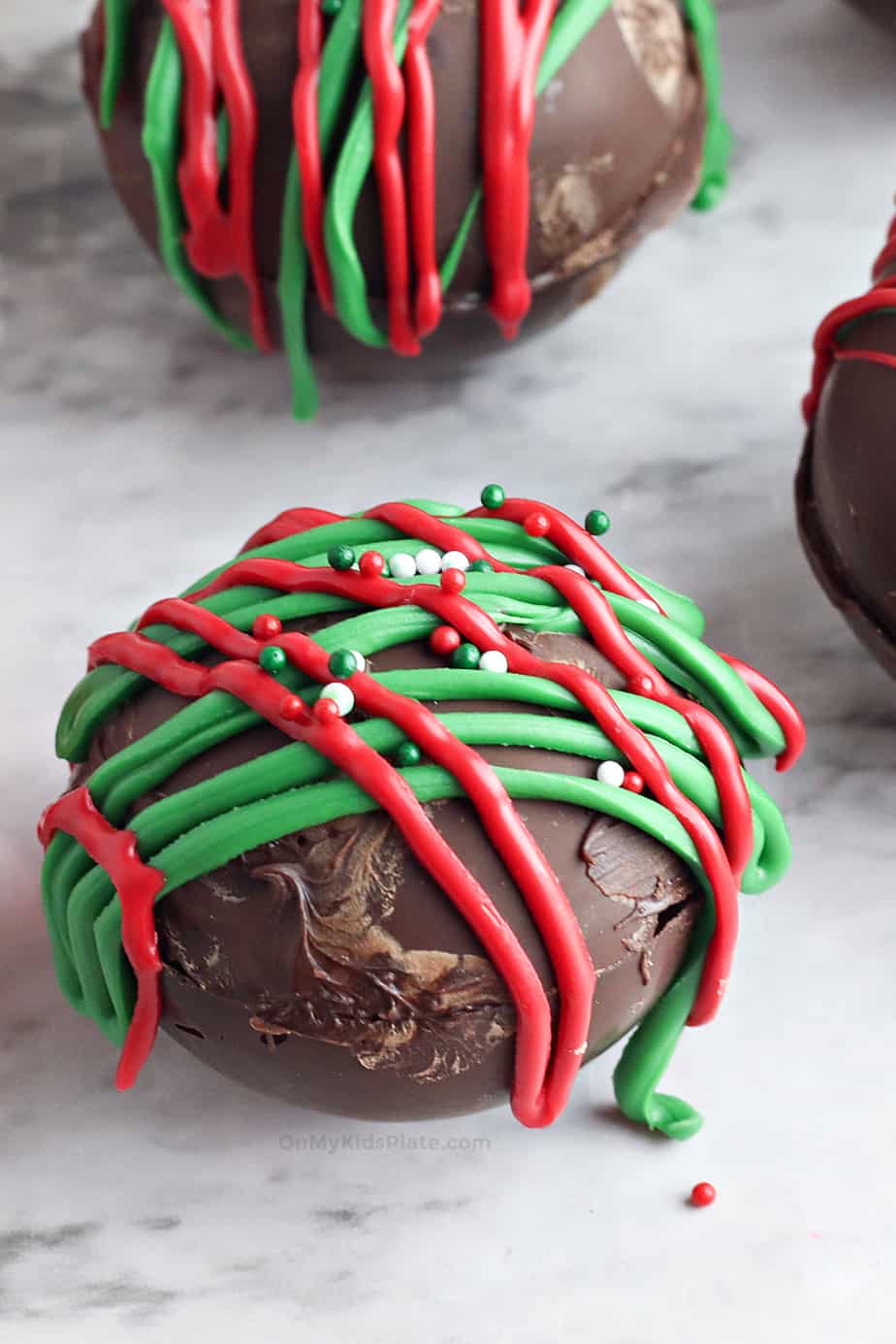 A homemade hot chocolate bomb drizzled with red and white icing.