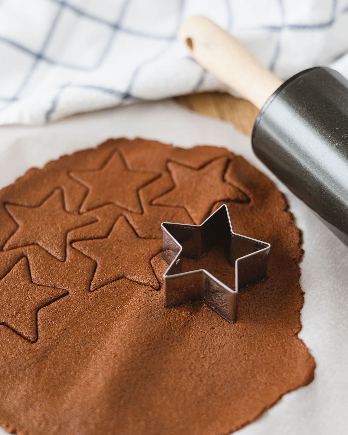 Rolling out 2-ingredient cinnamon-applesauce dough and cutting star shapes with a cookie cutter.