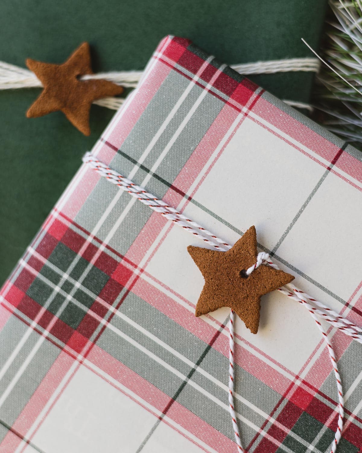A cinnamon ornament start cutout wrapped around a plaid package.