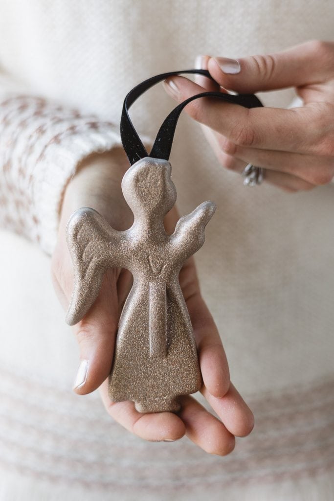 Holding an angel Christmas ornament made from a vintage cookie cutter and rose gold glitter spray paint.