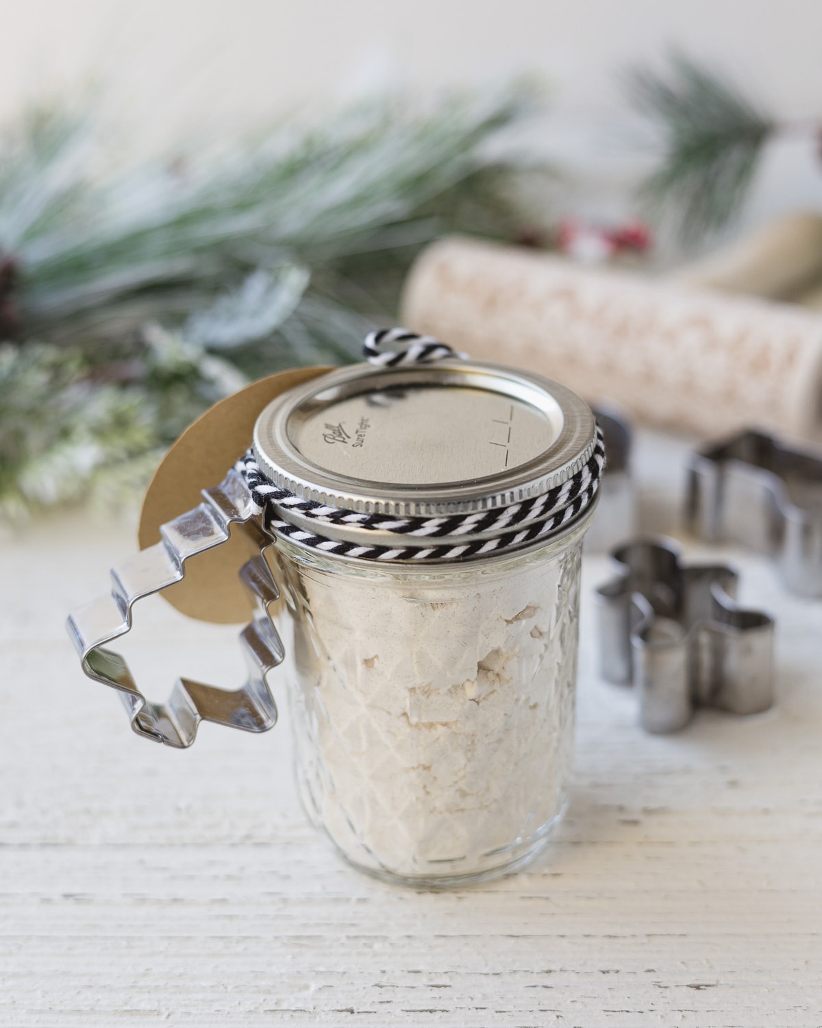 A jar of salt dough mix with a tag and cookie cutter.