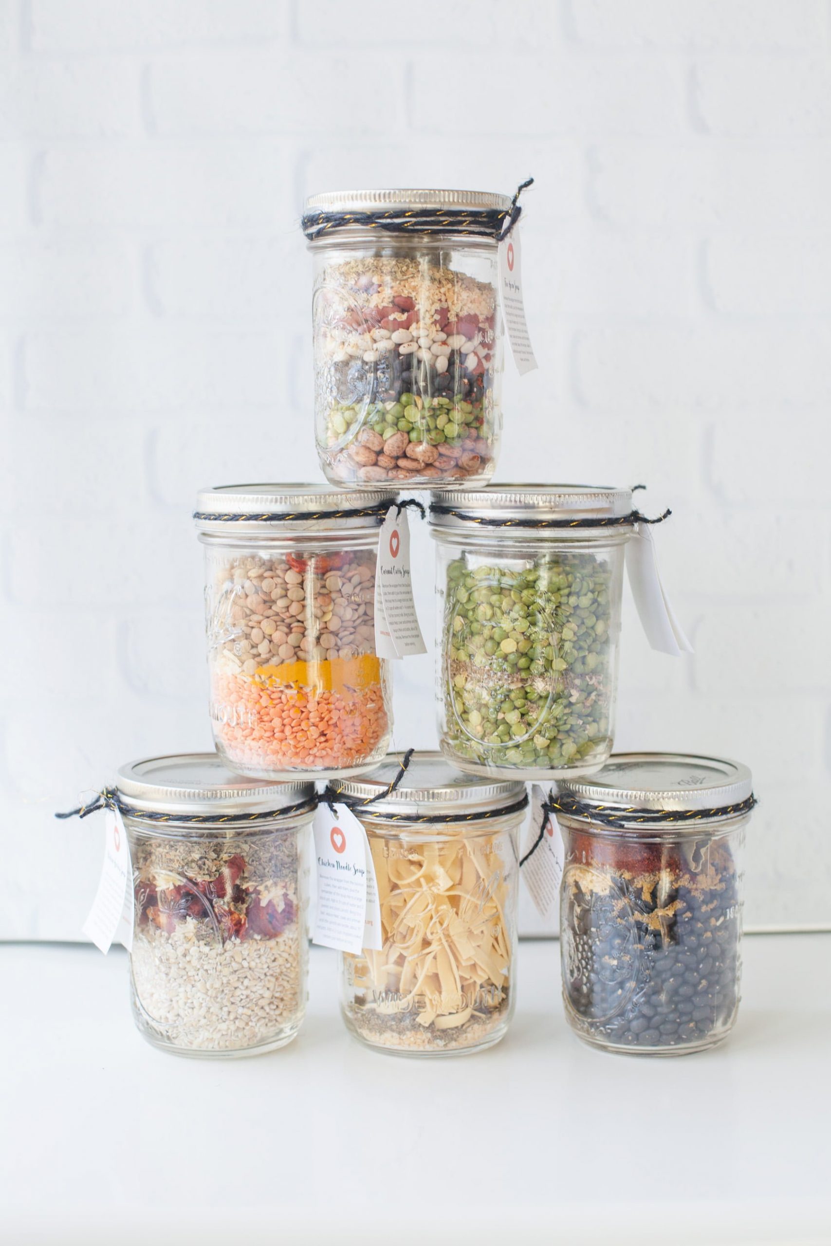 Six homemade soup mixes in jars arranged in a pyramid.