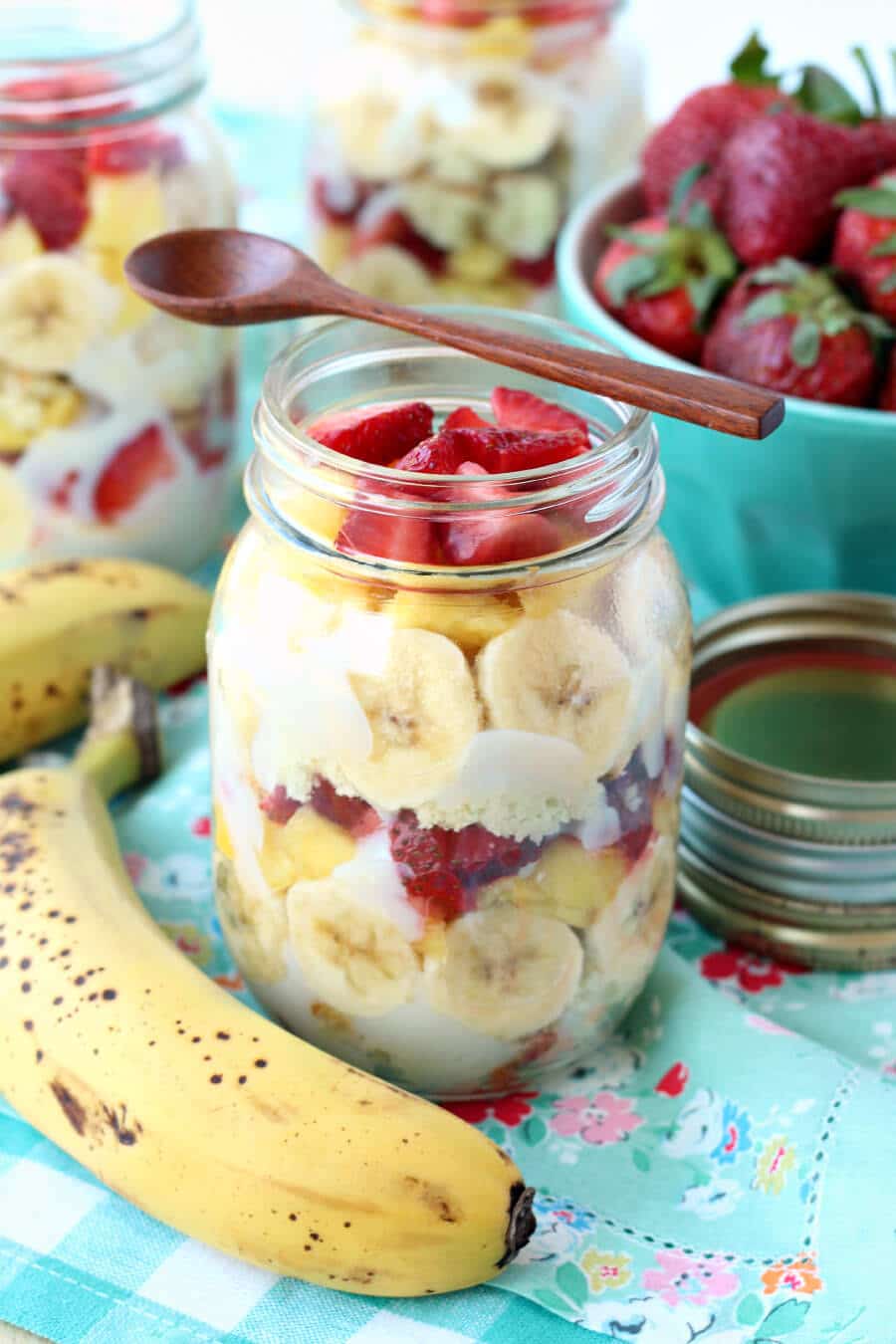 A banana and a mason jar filled with layers of cake, sliced bananas, and pudding.