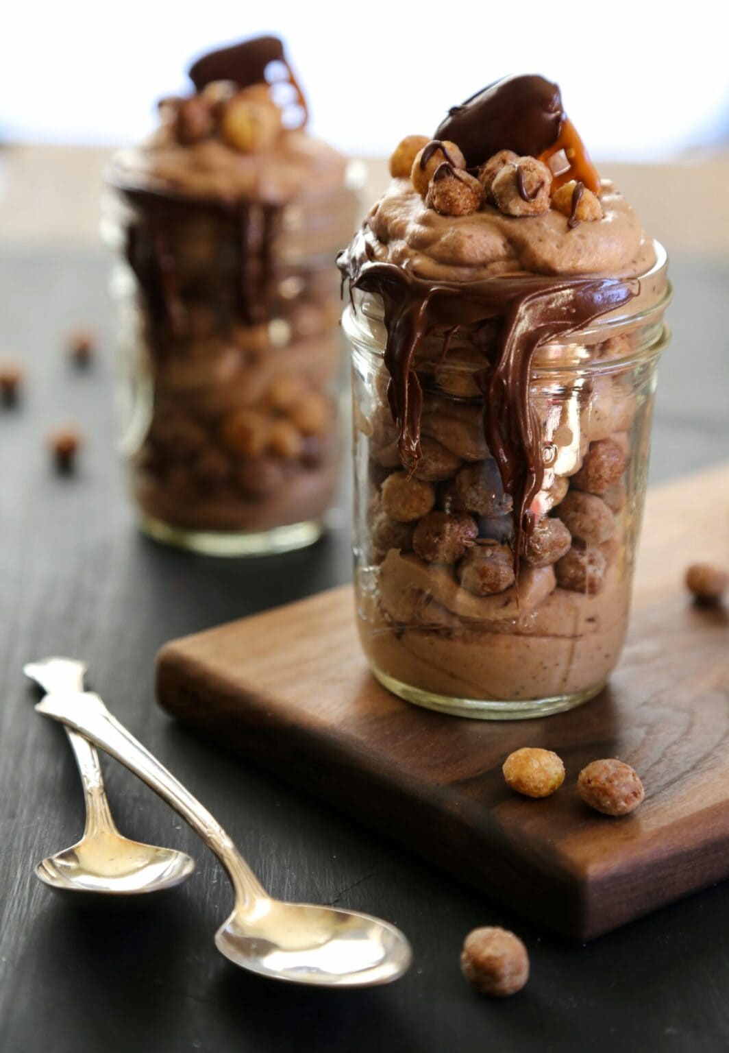 Chocolate mousse parfaits in mason jars with peanut butter puff cereal garnish.