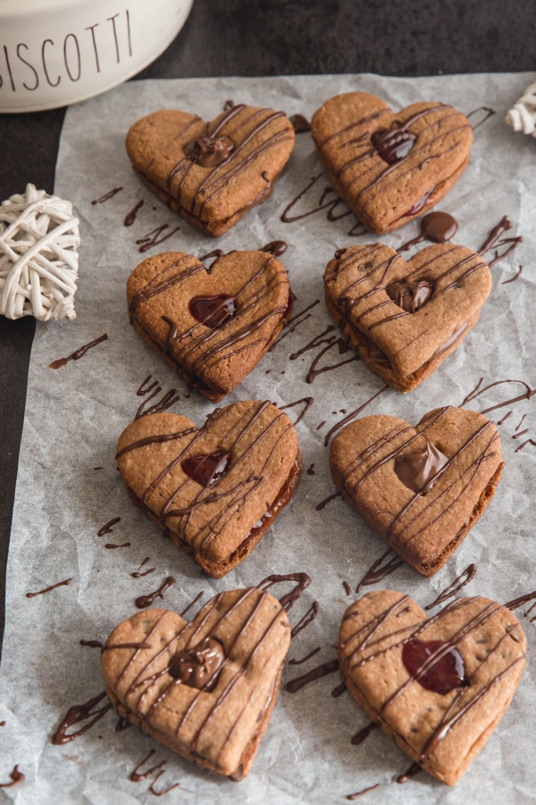 Chocolate sandwich cookies on parchment drizzled with more chocolate.