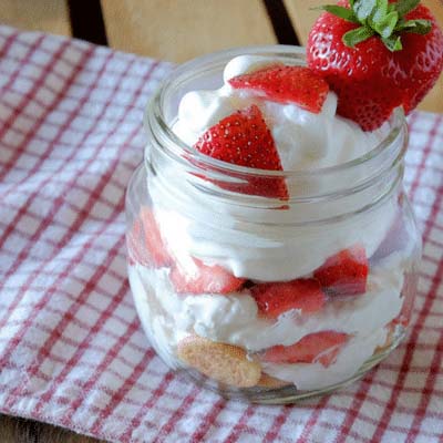 A mason jar filled with a layered strawberry shortcake.