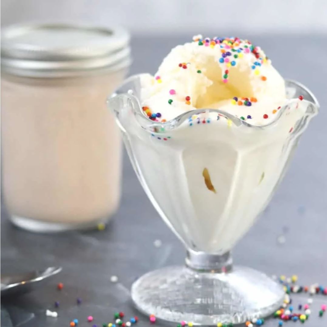 An ice cream cup filled with vanilla ice cream and sprinkles.