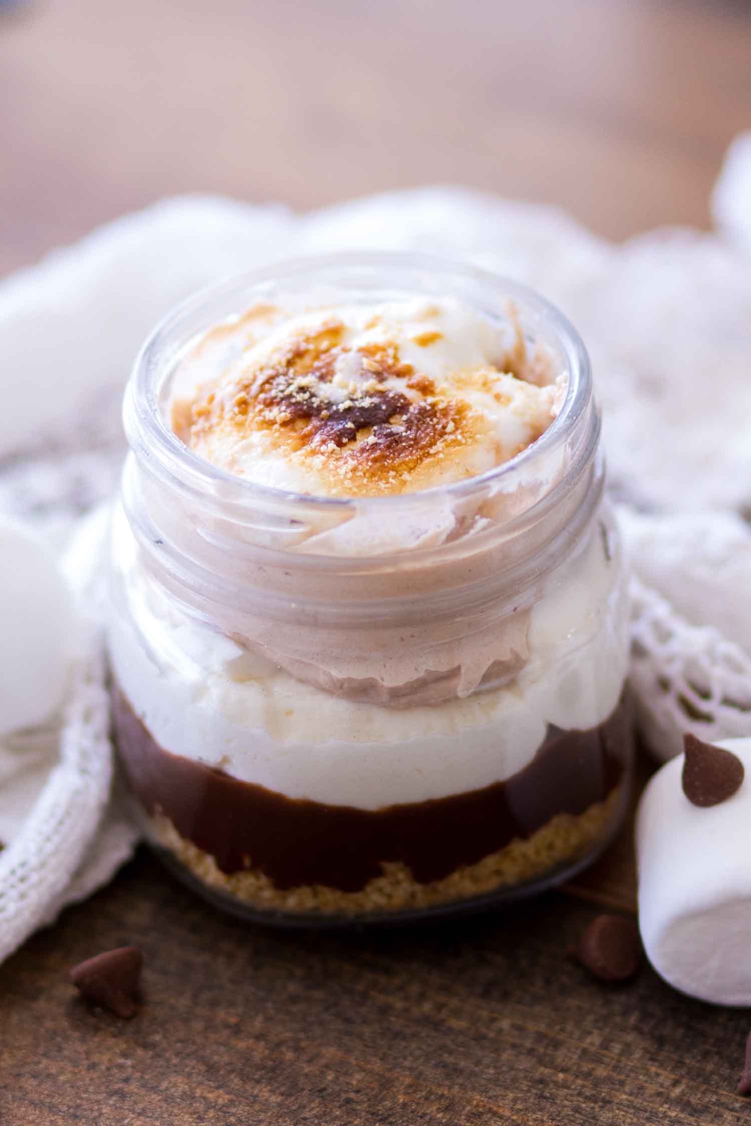 A s'mores mason jar dessert with layers of chocolate, marshmallow cream, and a graham cracker crust.