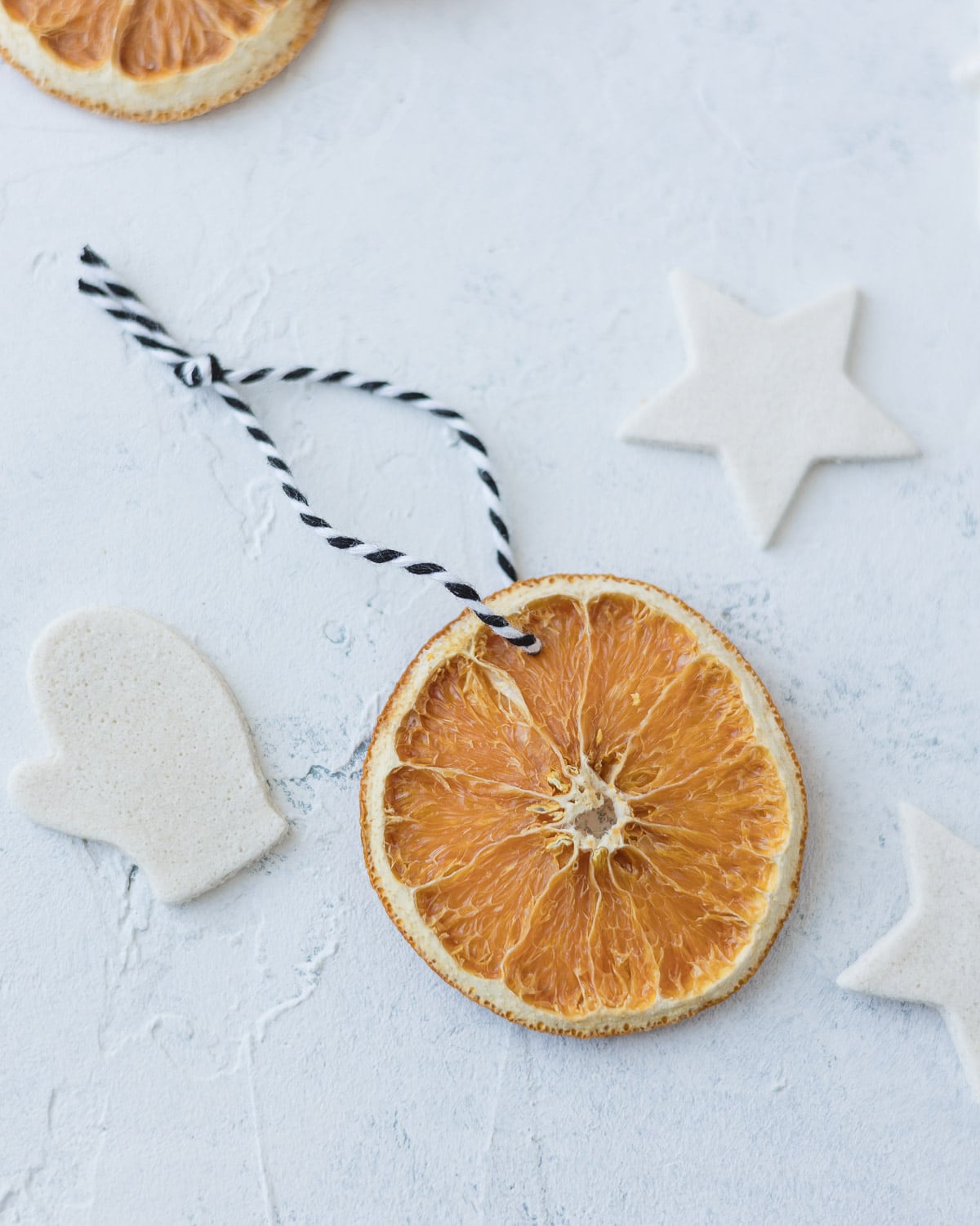 An orange slice ornament with a black-and-white string hanger.