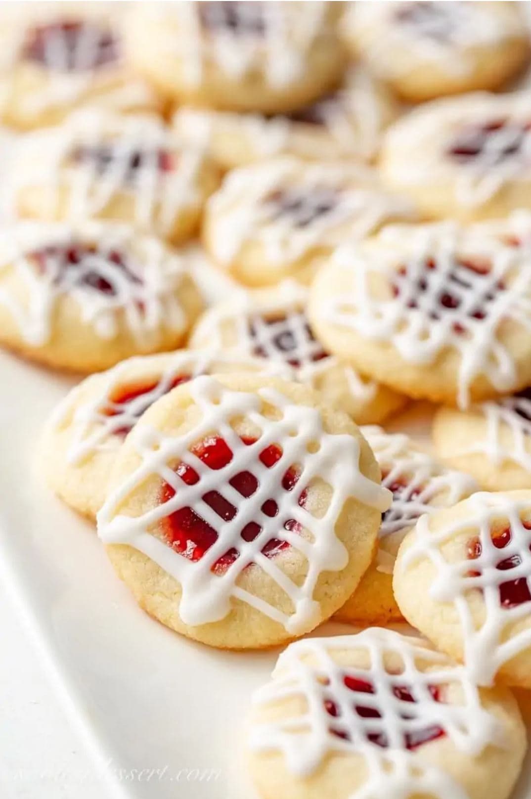 Raspberry Almond Thumbprint cookies decorated with a cross-hatching of glaze.