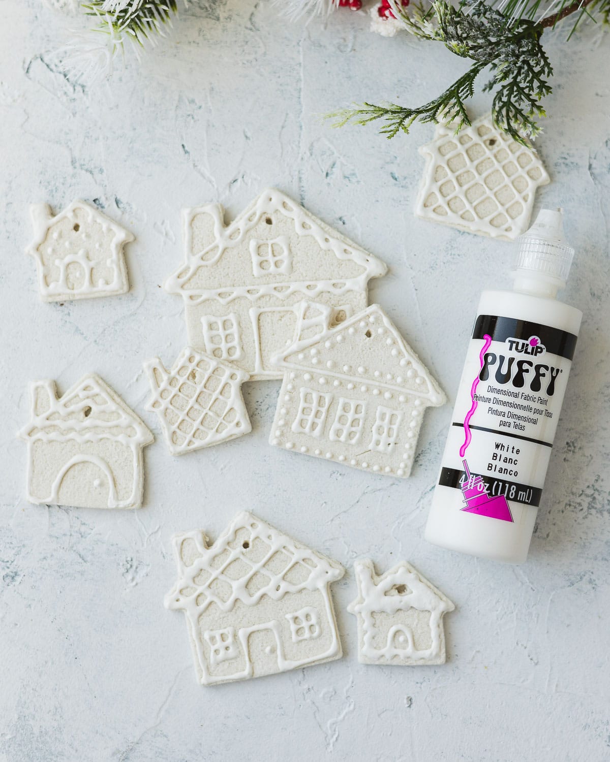 A bottle of white puffy paint and salt dough houses with puffy paint decorations.