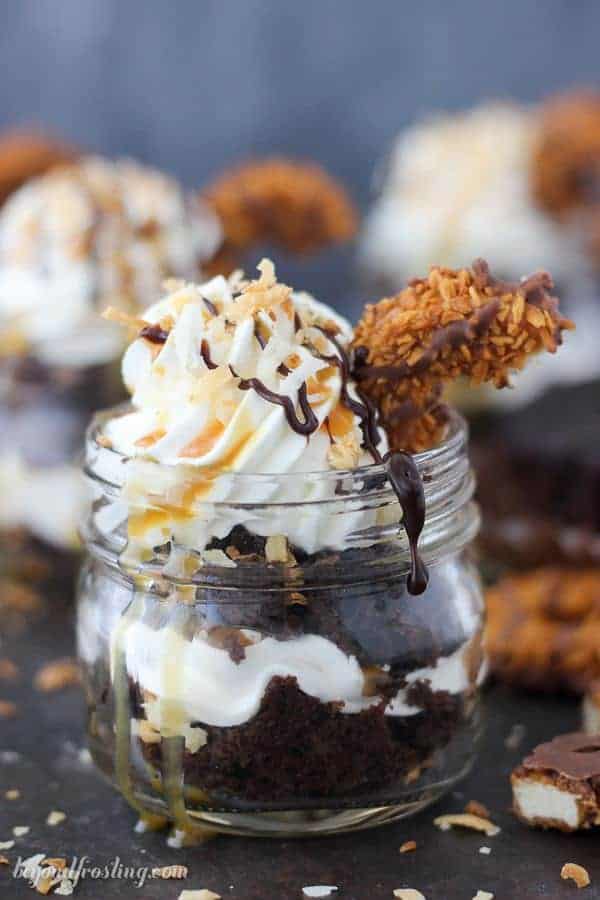 Jar filled with chocolate cake and topped with whipped cream and cookie pieces.