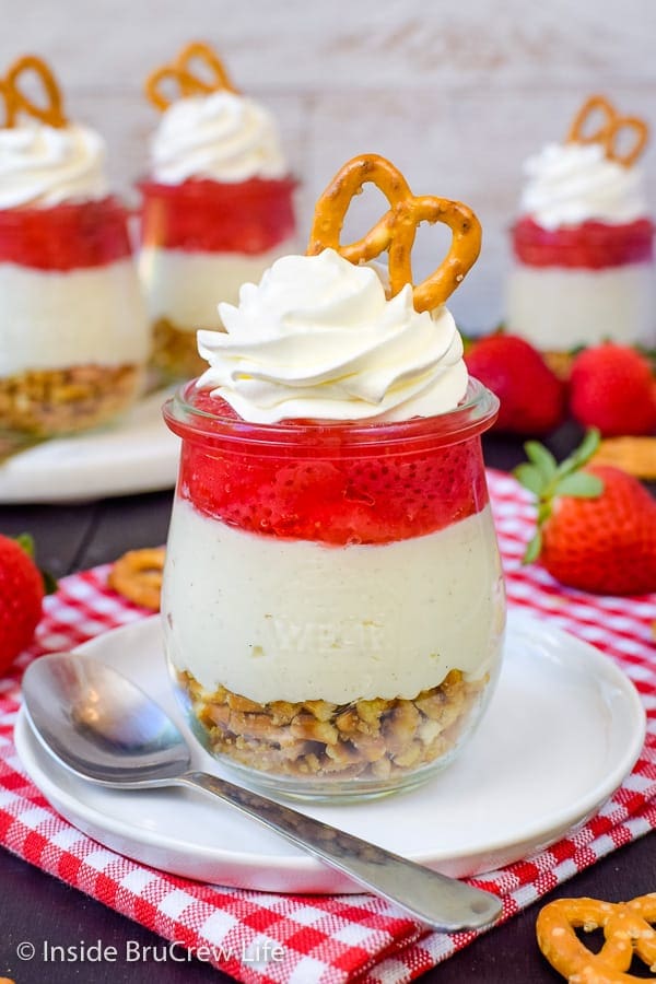 A layered strawberry pretzel dessert in a glass jar.