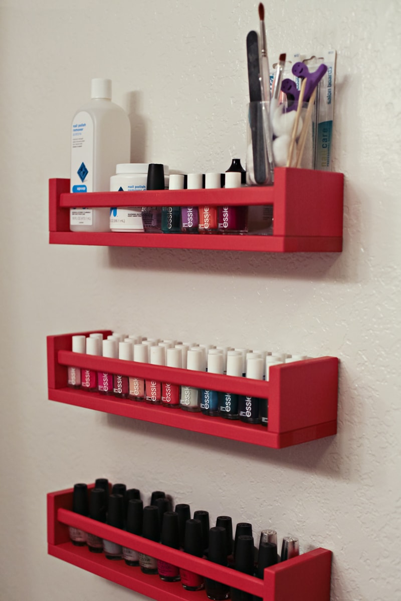 IKEA spice racks painted red, hung on a wall, and filled with nailpolish.