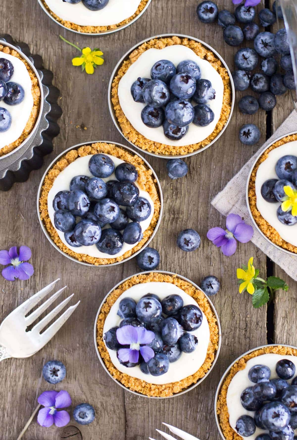 Mini blueberry tarts cooked in mason jar lids and topped with fresh blueberries.