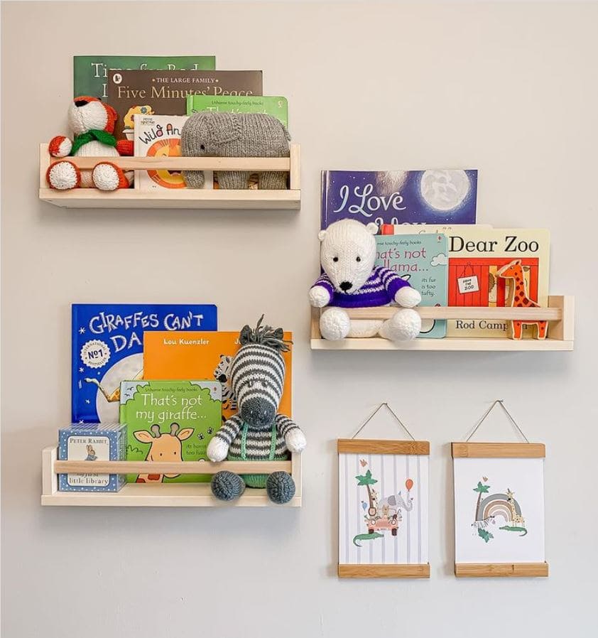 IKEA spice racks hung on a wall with children's books and stuffed animals inside.