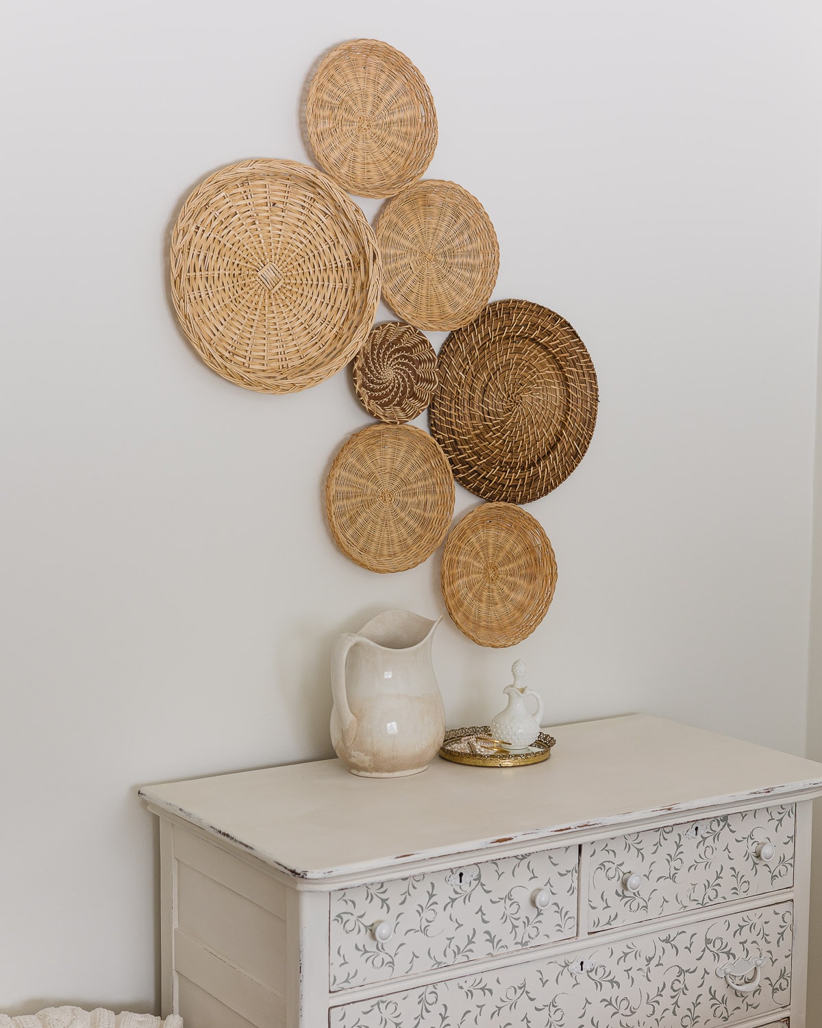 Seven vintage baskets hanging above a chalk-painted dresser.