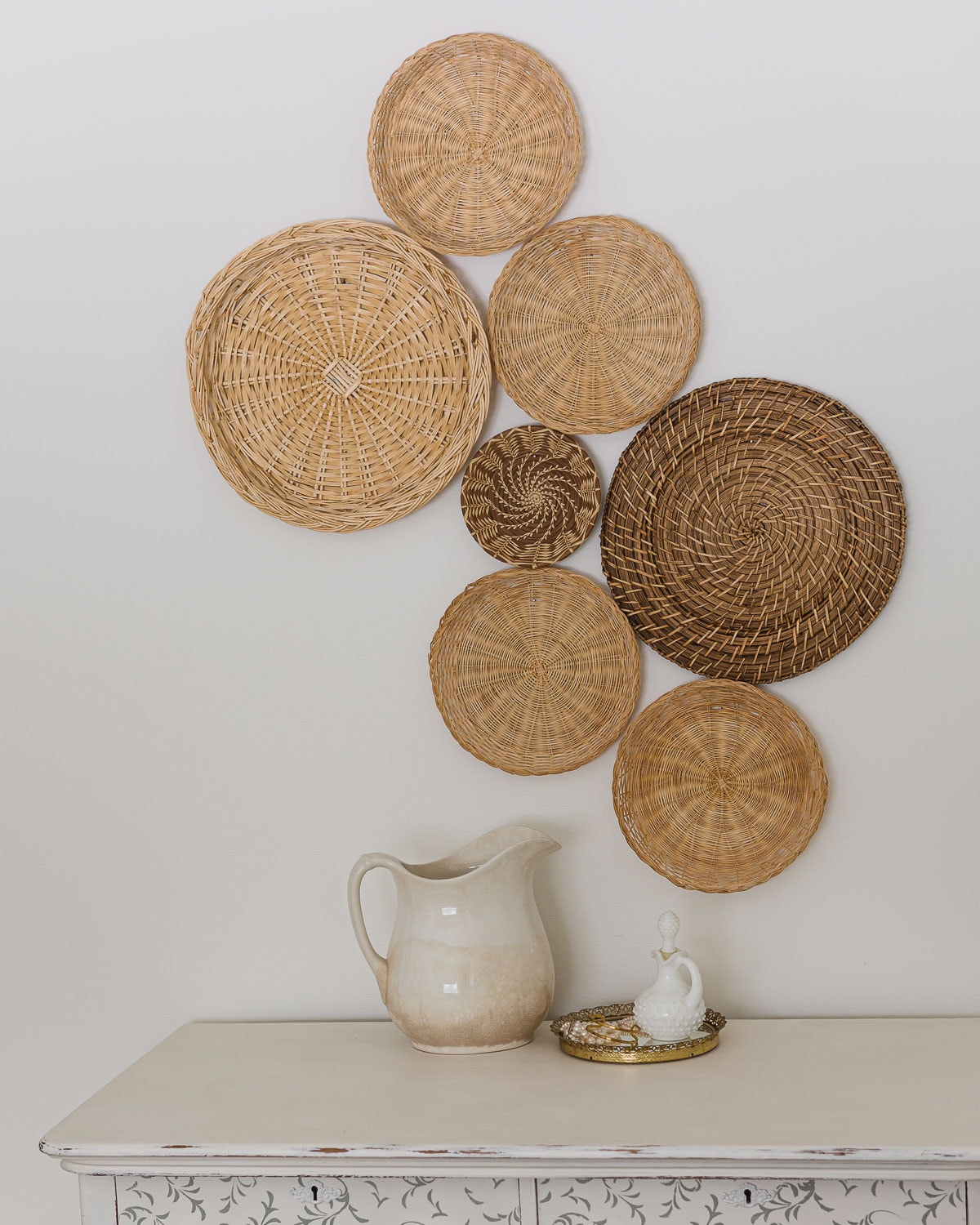 A selection of vintage baskets arranged into a basket gallery wall and hanging above a dresser.