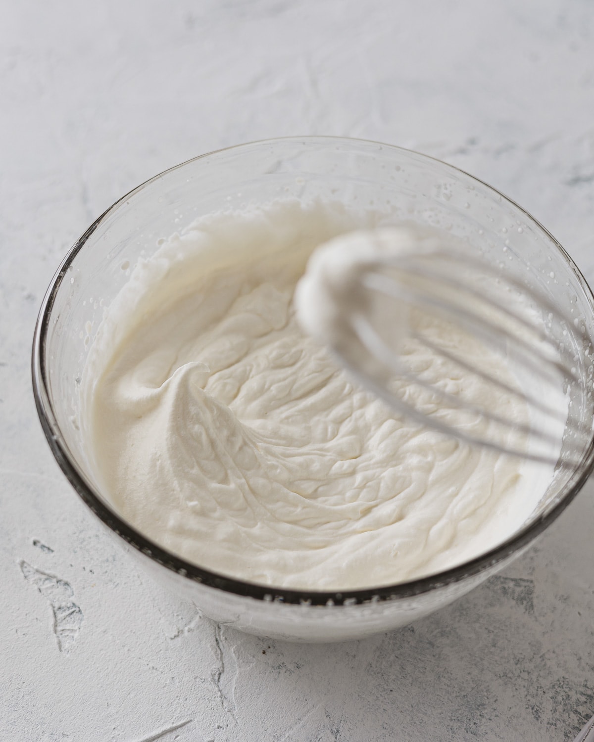 A bowl of whipped cream demonstrating medium peaks.