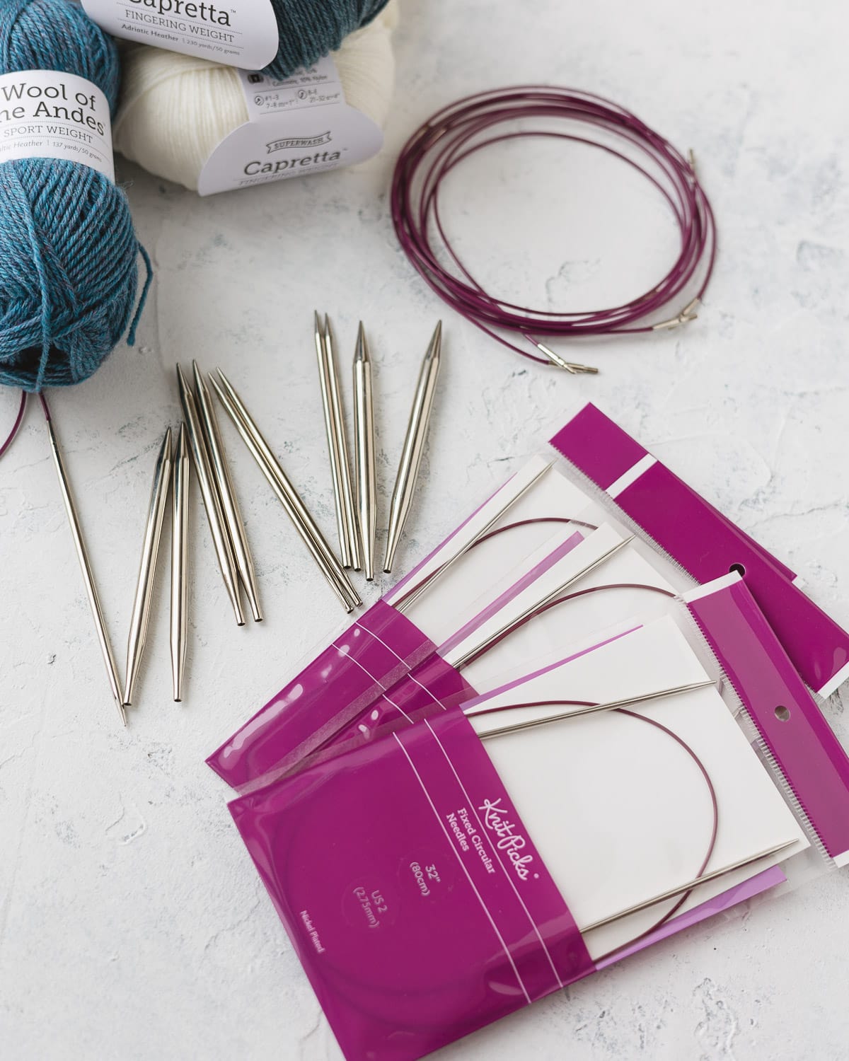 Nickel plated interchangeable knitting needle set, packages of fixed circular needles, cables, and yarn.