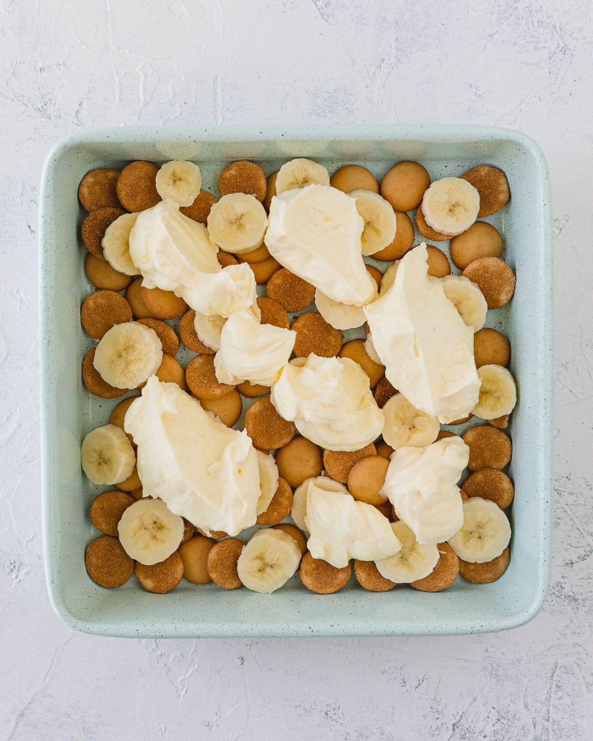 A square baking pan with layers of pudding, bananas, and vanilla wafers.