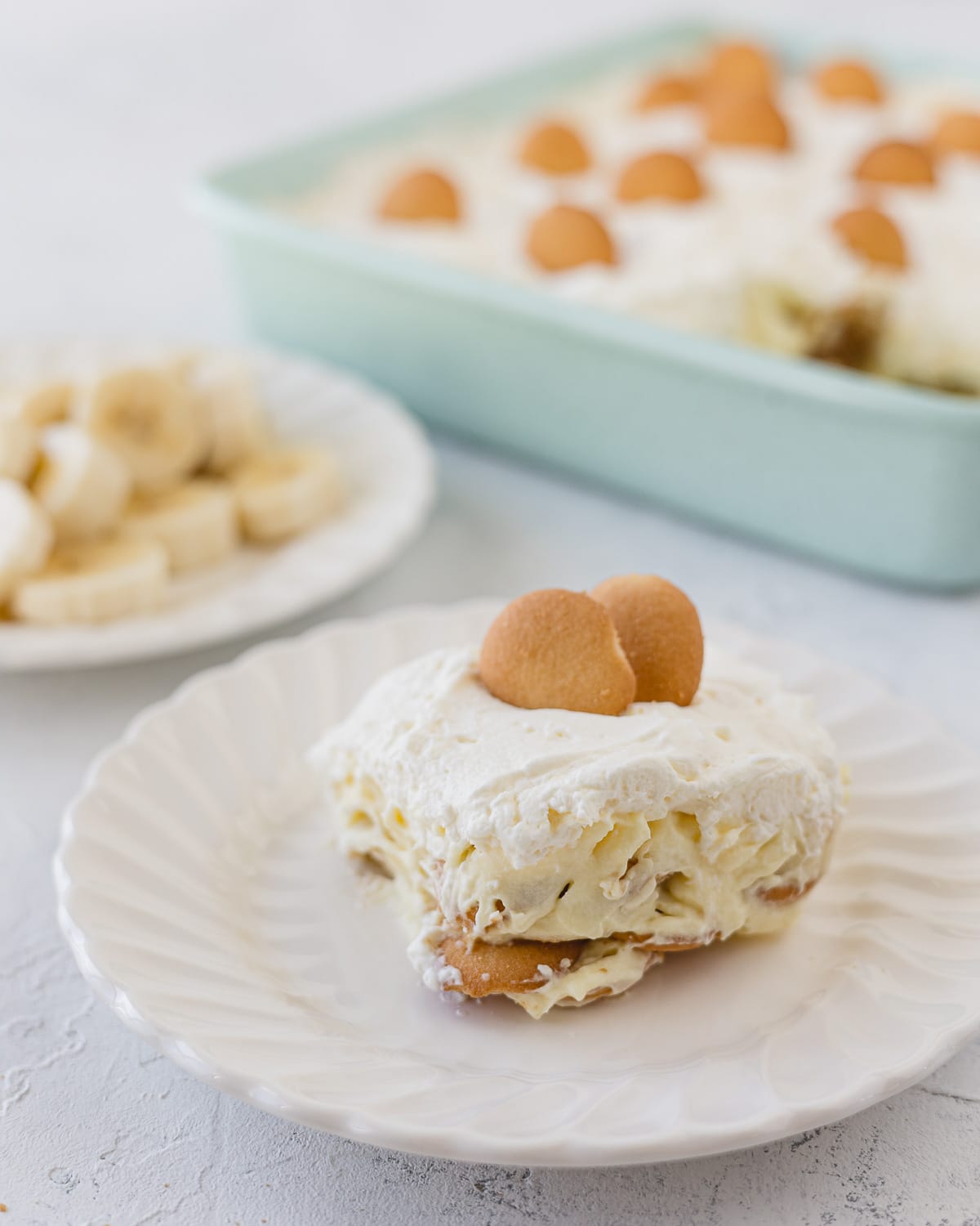 A slice of no bake banana pudding on a scalloped white plate.