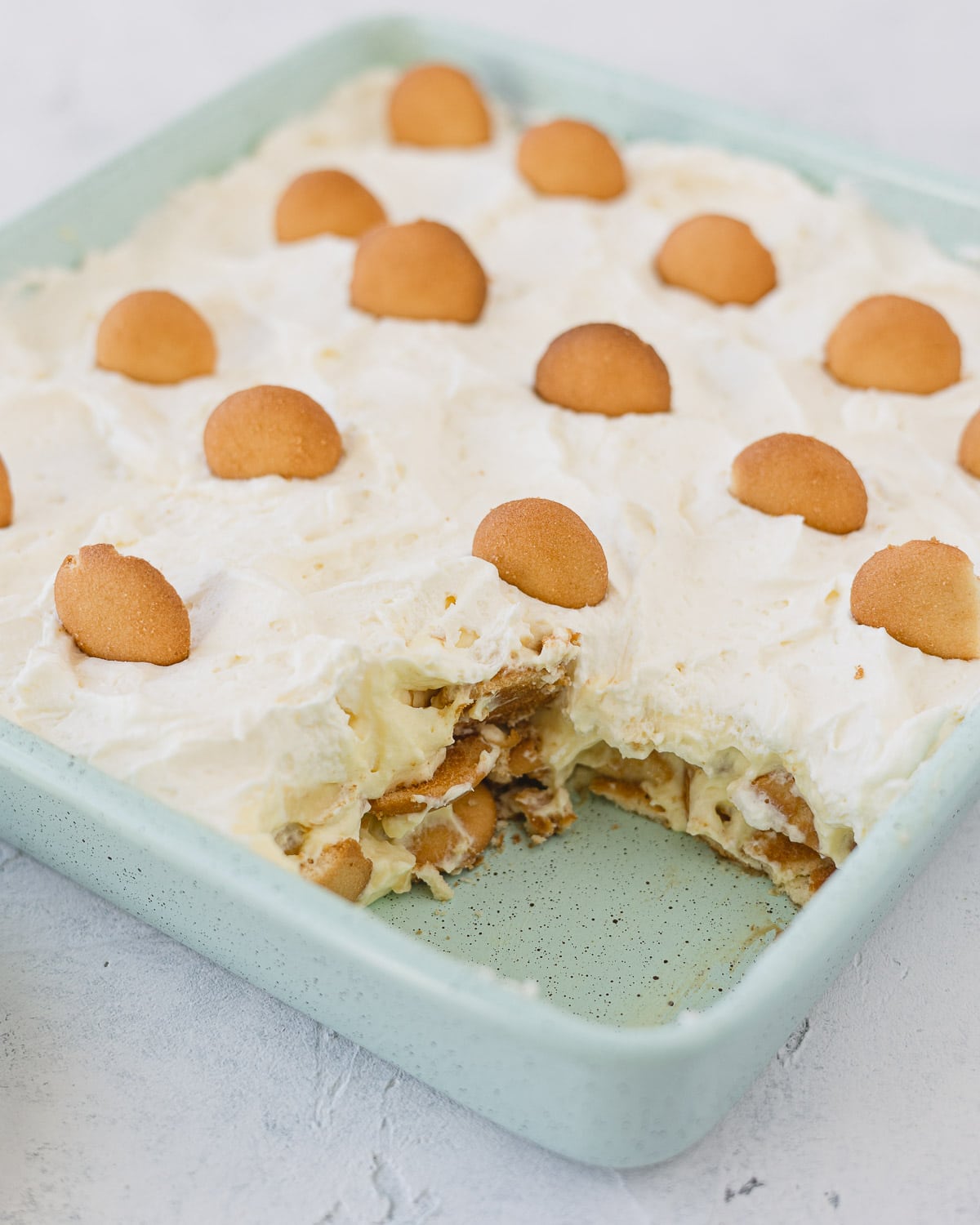 A robin's egg blue 8x8 pan with a slice of no bake banana pudding removed.