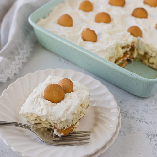 A slice of no bake banana pudding on a white plate with a fork.