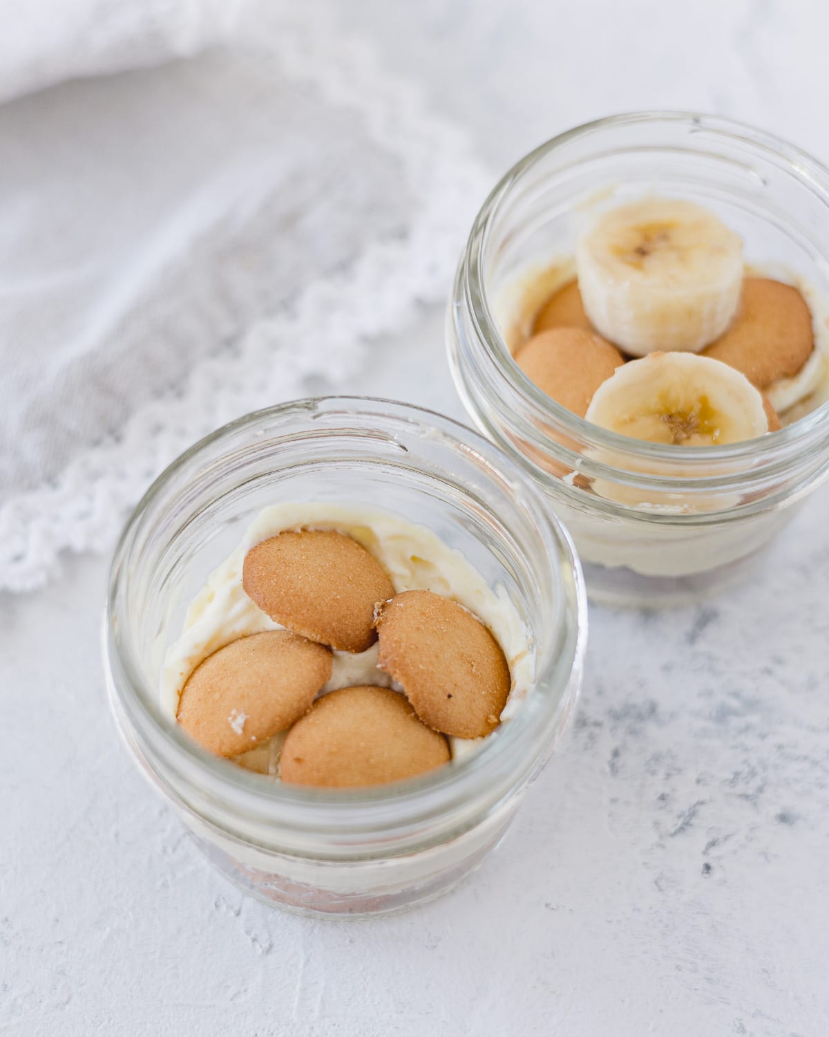 Small mason jars with layers of vanilla pudding, bananas, and vanilla wafers.