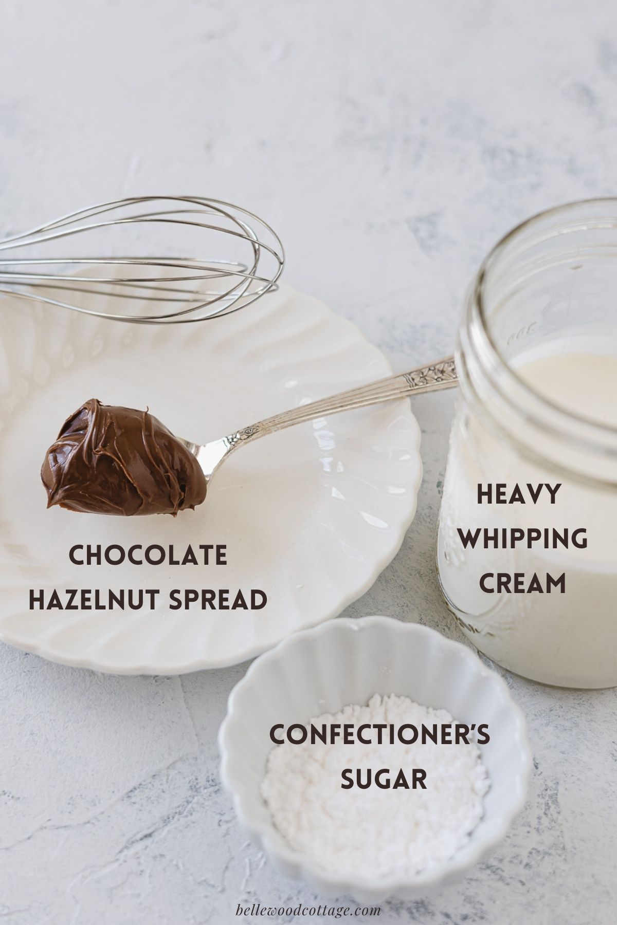 Labeled ingredients for Nutella Whipped Cream, a spoon of nutella, glass of heavy cream, and dish of powdered sugar.