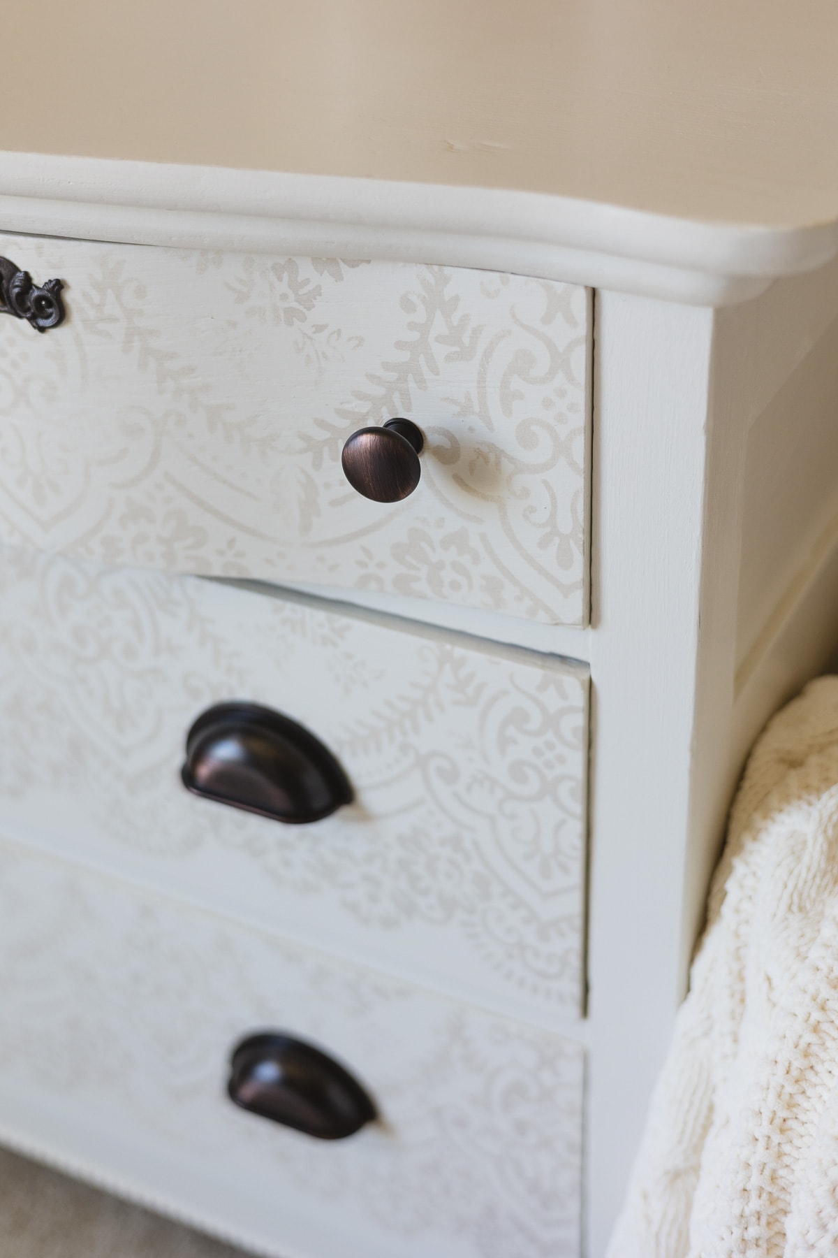 A white painted and stenciled dresser with oil rubbed bronze hardware.