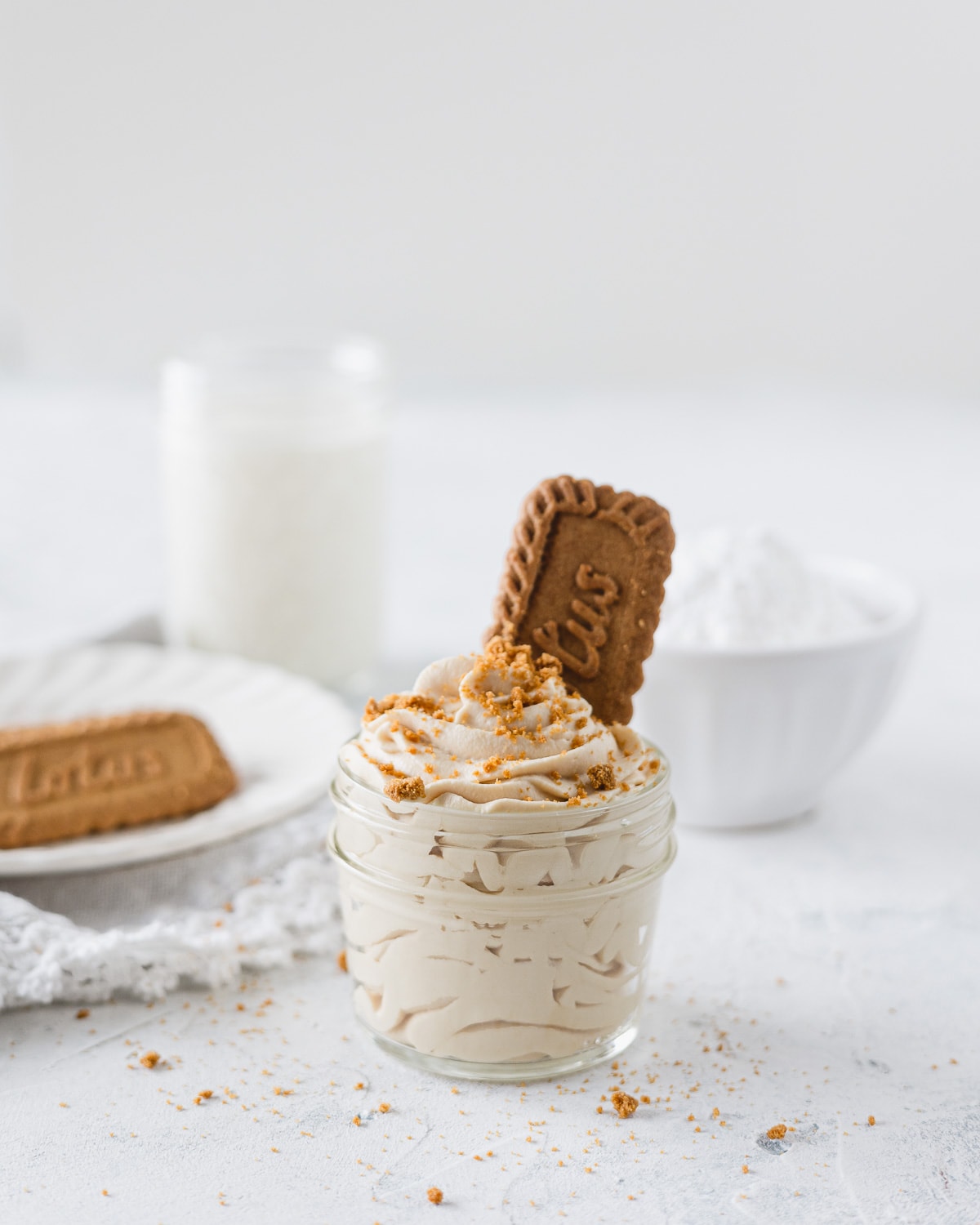 A small glass jar filled with cookie butter whipped cream and a cookie.