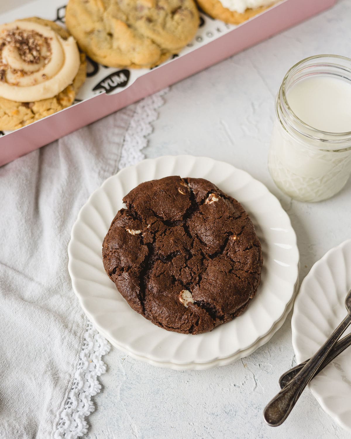 A large chocolate cookie with white and semi-sweet chips on a stack of white scalloped plates.