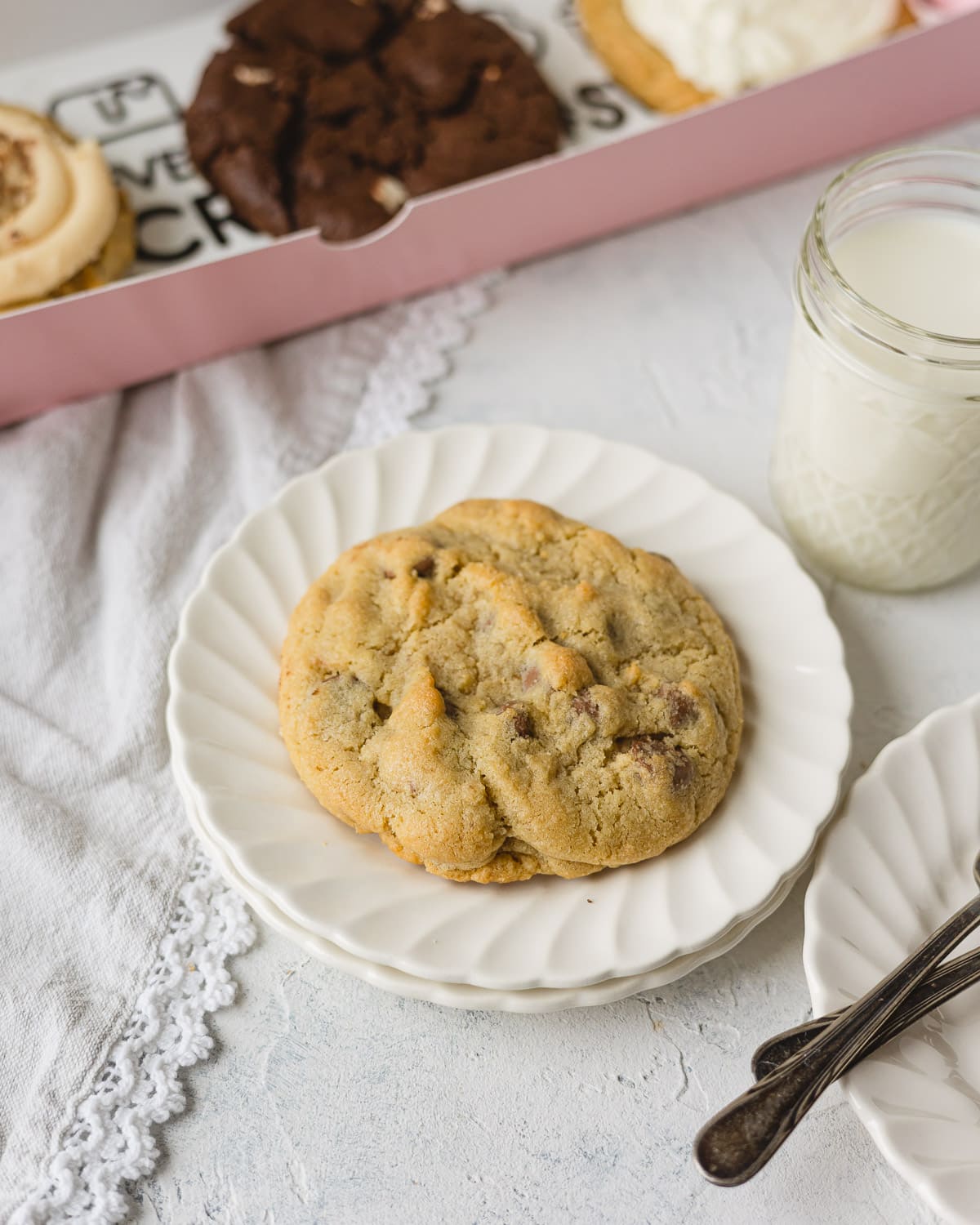 A chocolate chip bakery cookie on a stack of scalloped plates.