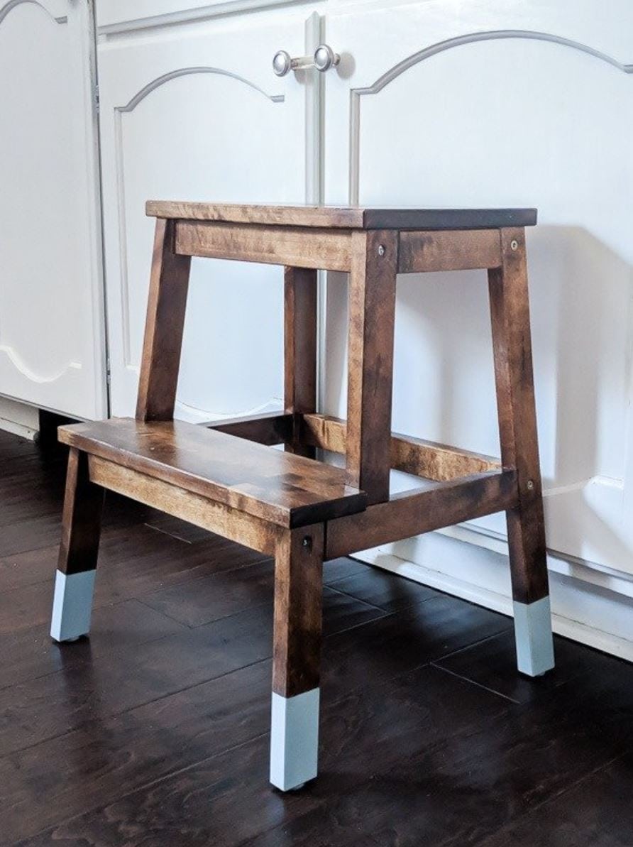 An IKEA step stool stained with a dark stained and painted with chalk paint on the feet.