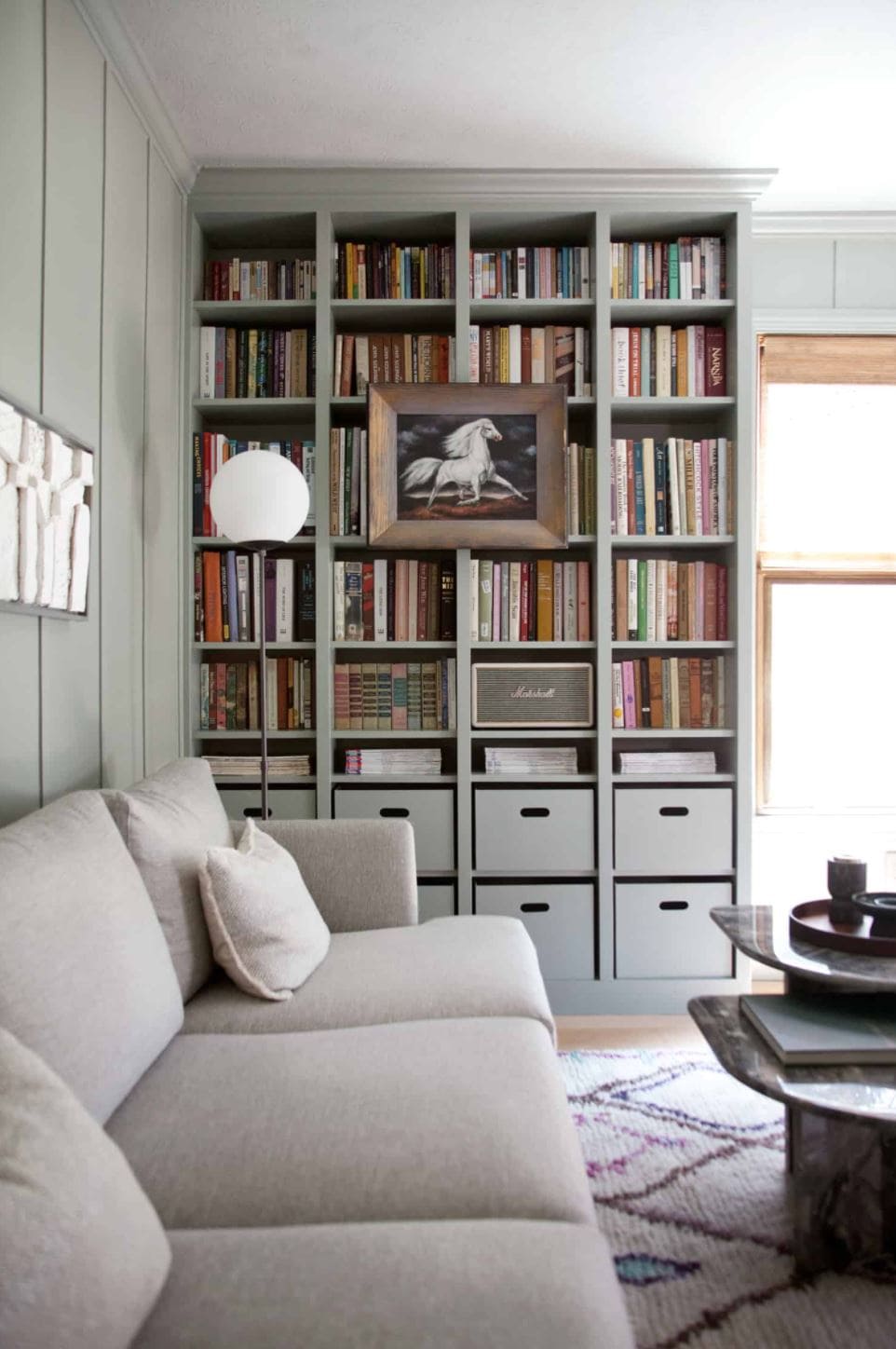 Built-in shelves painted a gray-green and filled with books and art.