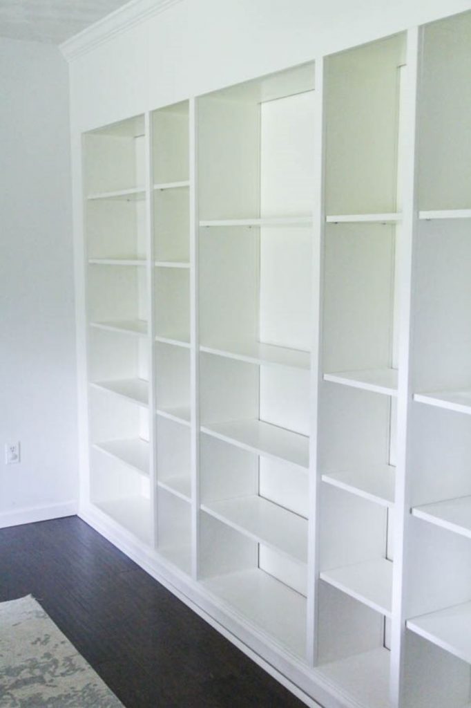Empty white built-in Billy bookcase shelves in a living room.